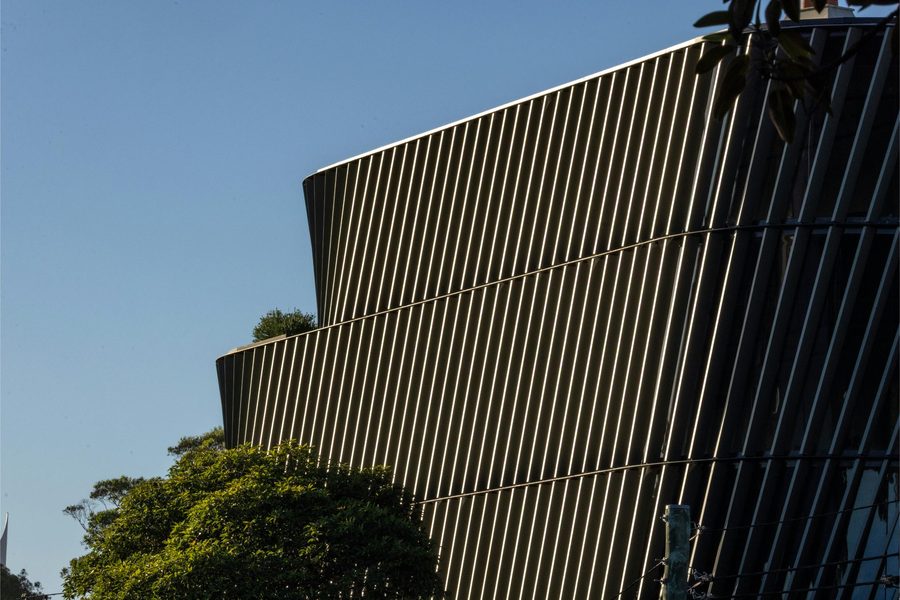 A modern building with an angled facade, framed by trees