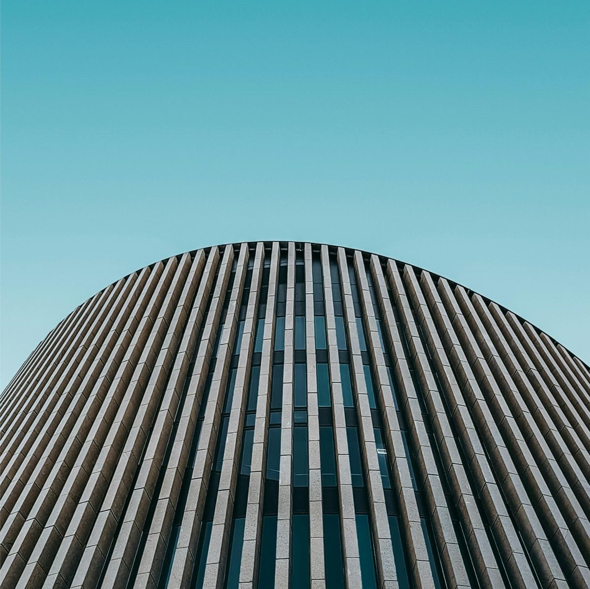 A curved office building clad in vertical fins