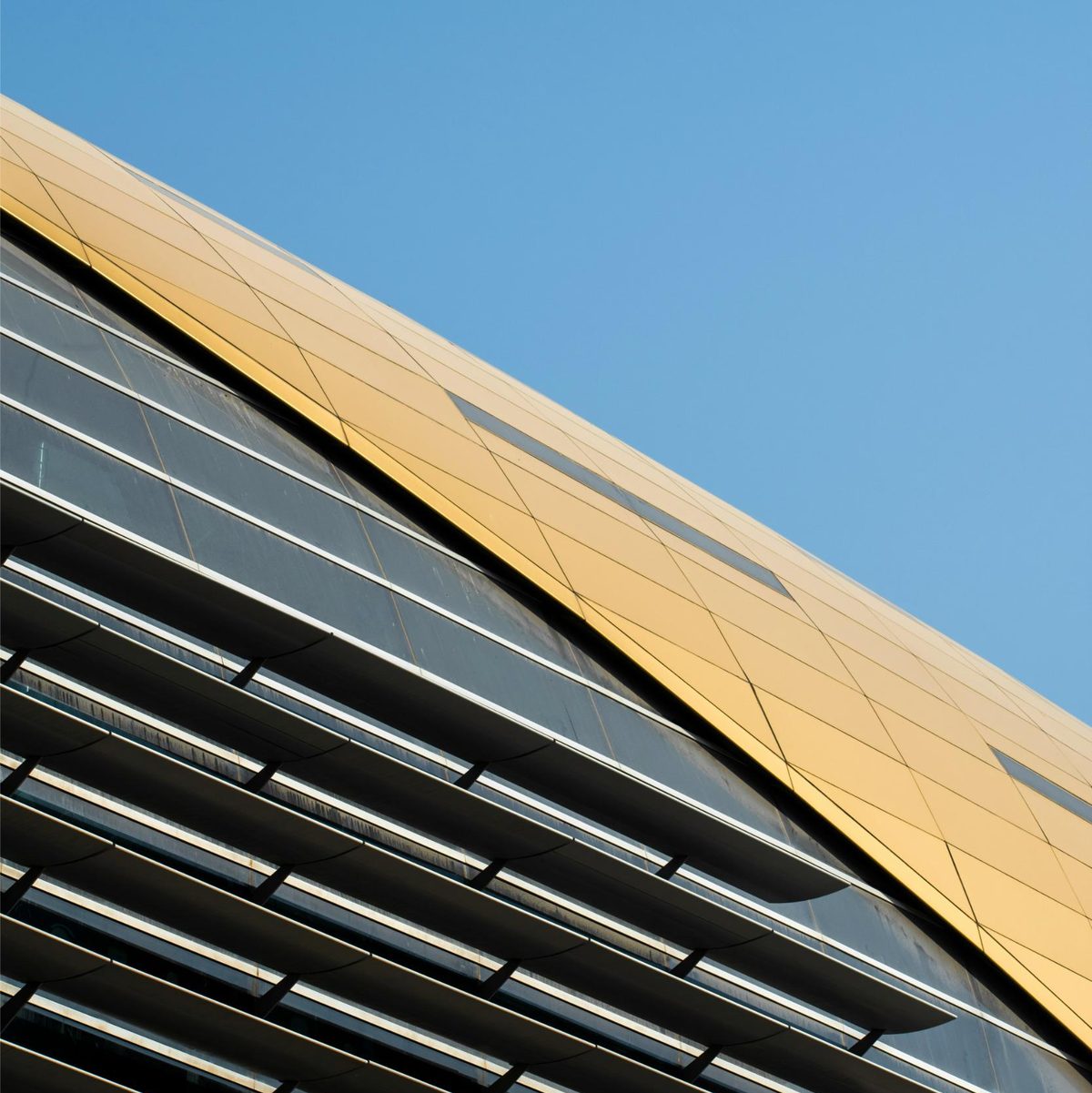 The angular metal roof of a modern building against a clear sky